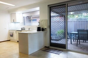 Una cocina con mostrador, pileta y una puerta corredera de vidrio que da a un patio exterior.