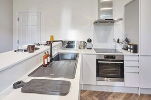 A modern kitchen with a stainless steel sink, a built-in oven, and a microwave. - Host & Stay | Apartment 2, Upton House (Northampton)