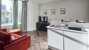Eine moderne Küche mit weißer Arbeitsplatte, Spüle und einem schwarzen Wasserhahn. Über der Arbeitsplatte hängen drei gerahmte Bilder an der Wand.