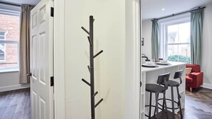 A modern kitchen with a white countertop, two bar stools, and a window with curtains. - Host & Stay | Apartment 3, Upton House (Northampton)