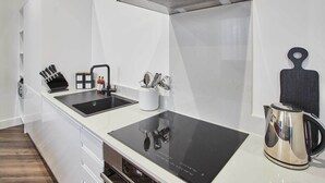 A modern kitchen with a black induction cooktop, a stainless steel kettle, and a knife block. - Host & Stay | Apartment 4, Upton House (Northampton)