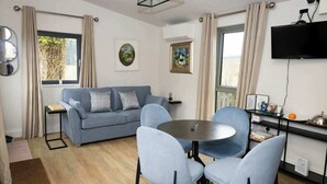 A modern living room with a grey sofa, two light blue chairs, a round table, and a flat-screen TV mounted on the wall. - Private Country Residence, Made 4 Luxury Gathering (Newcastle West)