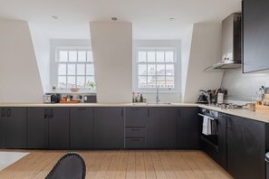 A modern kitchen with dark cabinets, a wooden countertop, and a large window providing natural light.