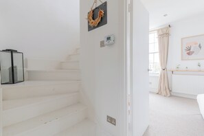 A staircase leading to a bedroom with a bed, a radiator, and a window with curtains. - Perfect 2BD Duplex with Private Balcony, Islington (Greater London)