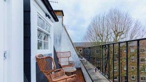 A balcony with wicker chairs and a small table, overlooking a residential area with buildings and bare trees. - Perfect 2BD Duplex with Private Balcony, Islington (Greater London)