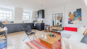 A modern living space with a kitchen, dining area, and a large window. - Perfect 2BD Duplex with Private Balcony, Islington (Greater London)