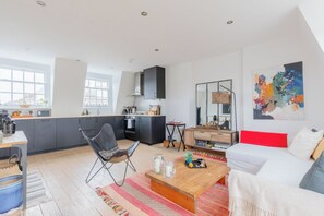 A modern living space with a kitchen, dining area, and a large window.
