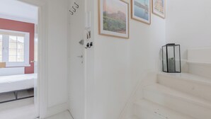 A white room with a bed, a door, and a staircase. There are framed pictures on the wall. - Perfect 2BD Duplex with Private Balcony, Islington (Greater London)