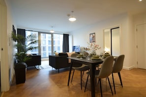 A modern dining area with a table set for four, a sofa, and a potted plant.