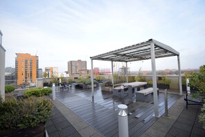 Une terrasse sur le toit, dotée d’un espace extérieur aménagé avec des sièges, des jardinières et une structure en forme de pergola.