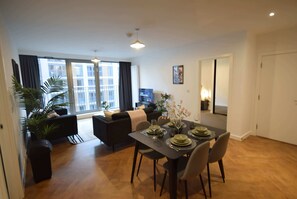 Un salon moderne avec un coin repas, de grandes fenêtres et une vue sur la ville.
