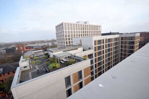 Ein mehrst öckiges Gebäude mit Dachterrasse, Sitzgelegenheiten und Bepflanzung.