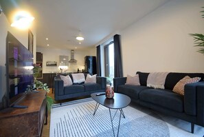 Un salon moderne avec un canapé, une table basse et un téléviseur.