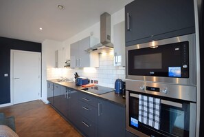 Une cuisine moderne équipée d’appareils électroménagers en acier inoxydable, d’un four encastré et d’un four à micro-ondes.