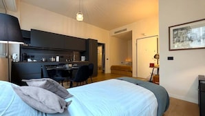 Habitació d'hotel moderna amb un llit gran, escriptori i petita cuina.