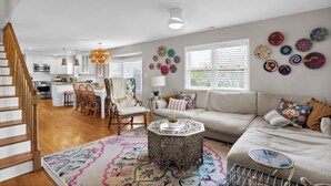 A spacious living area with a sofa, coffee table, and decorative wall art. - Seasaw Cottage - 5 bedroom pet friendly home on Wrightsville Beach (Wrightsville Beach)