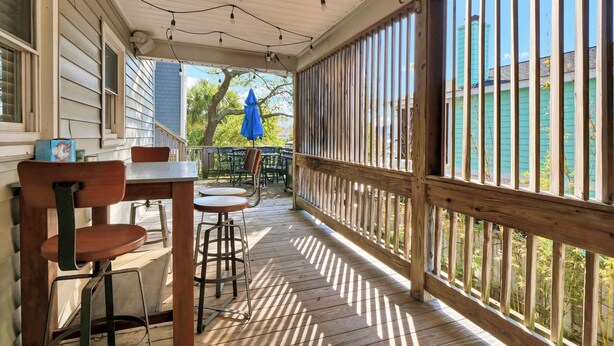 A covered outdoor area with a wooden deck, a table with chairs, and a blue umbrella. - Seasaw Cottage - 5 bedroom pet friendly home on Wrightsville Beach (Wrightsville Beach)