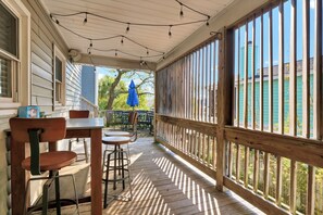 A covered outdoor area with a wooden deck, a table with chairs, and a blue umbrella.