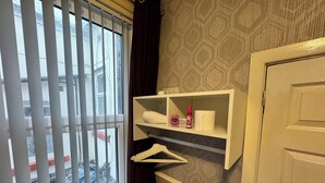 Une salle de bain avec une fenêtre, une étagère contenant des articles de toilette et une porte.