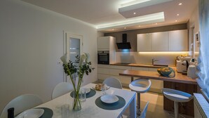 A modern kitchen with white cabinets, a built-in oven, and a central island with a sink. - Beautiful Villa Suton with a Private Pool (Pula)