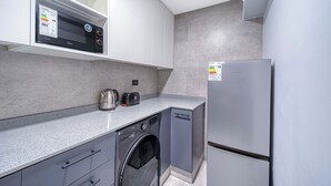 Cocina compacta con lavadora, refrigerador y microondas.