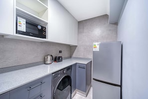 Une cuisine compacte équipée d’un lave-linge, d’un réfrigérateur et d’un four à micro-ondes.