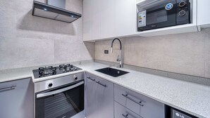 Una cocina moderna con estufa a gas, horno, pileta y un microondas sobre la encimera.