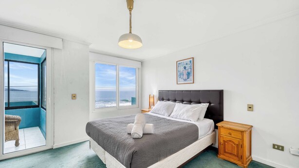 Une chambre à coucher comprenant un lit, une table de chevet, une commode, une fenêtre avec vue et un luminaire au plafond.