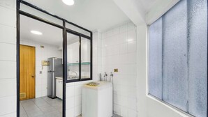 Une petite salle de bain aux carreaux blancs, avec un lavabo, des toilettes et une fenêtre en verre dépoli.