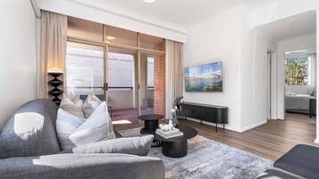A modern living room with a sofa, coffee table, and a painting on the wall.