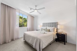 Relax in comfort with a large bed, tufted headboard, and matching bedside table.