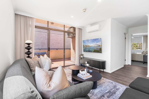 Relax in this stylish living space with a comfortable sofa, round coffee table, and large window offering a view of the city.