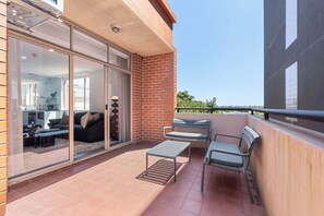 Un balcon doté d’une porte-fenêtre coulissante donnant sur un espace de vie, une petite table et deux chaises.