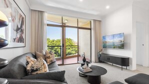 A modern living room with a grey sofa, a round coffee table, and a TV mounted on the wall. - Camperdown Cozy Corner 8 (Camperdown)