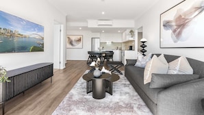A modern living room with a grey sofa, a coffee table, and a dining area with a black table and chairs.