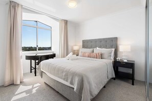 A modern hotel room with a large bed, a desk, and a view of the city. - Camperdown Cozy Corner 10 (Camperdown)
