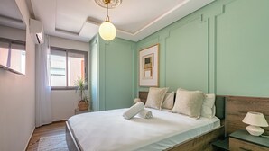 A bedroom with a large bed, a bedside table with a lamp, a framed picture on the wall, and a potted plant. - Appartement de luxe au centre de Gueliz  (Marrakech)