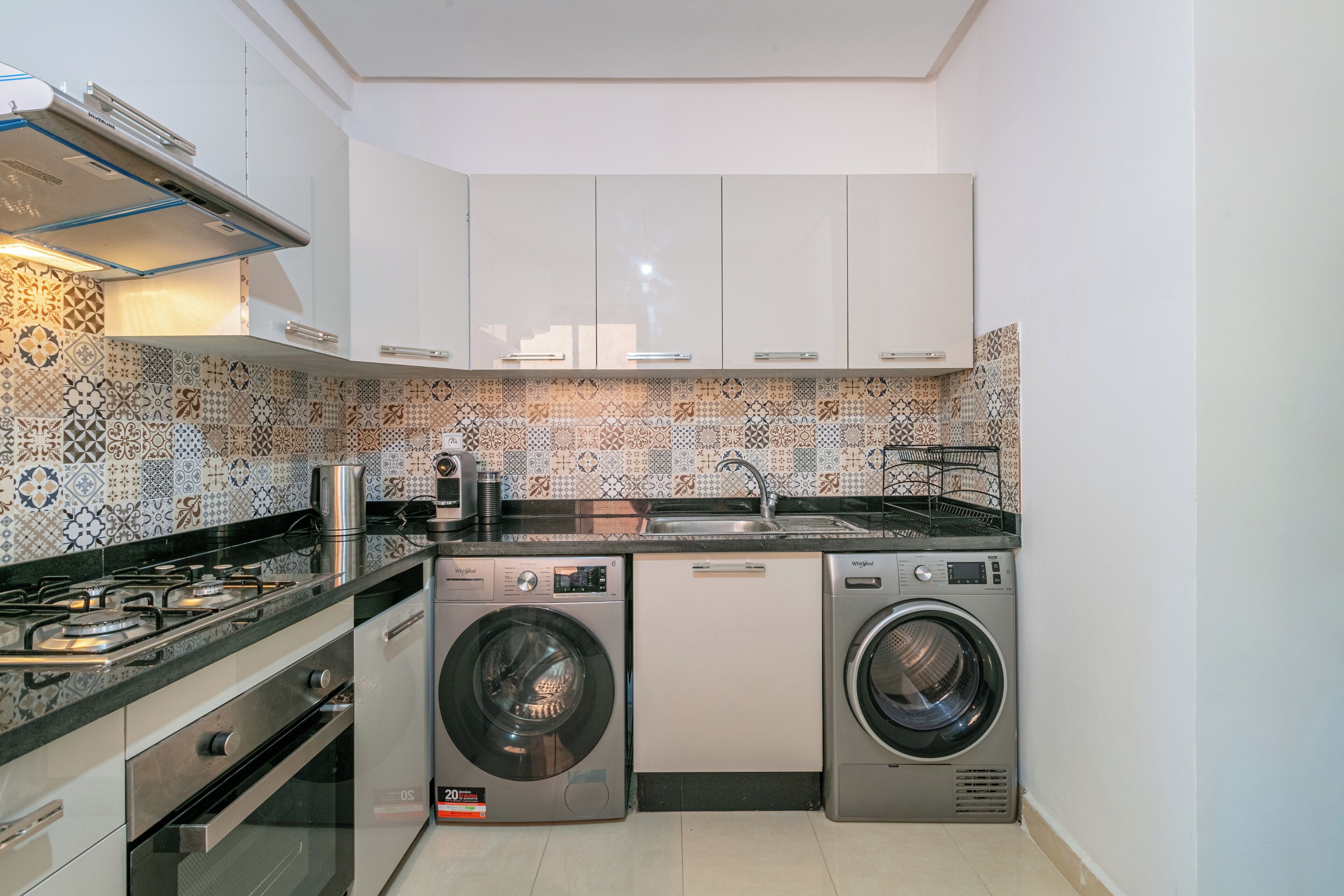 Una cocina compacta con estufa a gas, lavadora y lavavajillas.