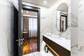 Ein modernes Badezimmer mit Marmorboden, einem Holztisch und einem großen Spiegel sowie einer Duschkabine.