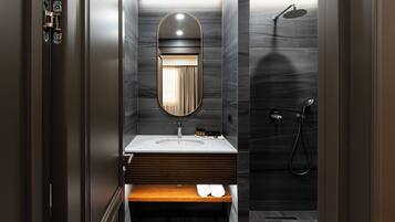 A modern bathroom with a vanity, mirror, shower, and a towel rack.