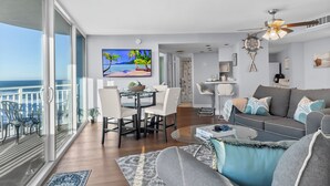 A modern living room with a balcony, a dining area, and a kitchen. - The Serenity at Peck Plaza (Daytona Beach)