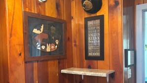 Un intérieur en bois agrémenté d’une décoration représentant un ours, d’un tableau encadré et d’une étagère.