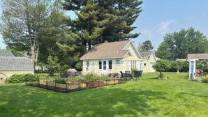 Il s’agit d’une propriété résidentielle dotée d’une pelouse bien entretenue, d’un potager et d’un espace patio aménagé avec du mobilier d’extérieur.