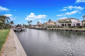 A waterfront property with a dock, a grassy area, and several buildings with a modern design. - Exquisite Waterfront Home | Featuring Pool/Hot Tub (Marco Island)