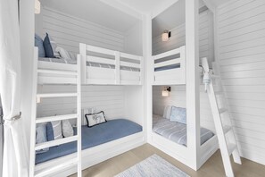 Une chambre avec des lits superposés, une échelle et un petit tapis.