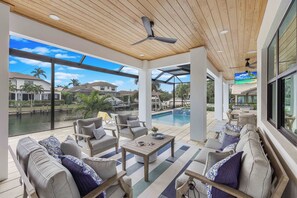 Une vaste terrasse extérieure dotée d’une piscine, de sièges confortables et d’un ventilateur de plafond.