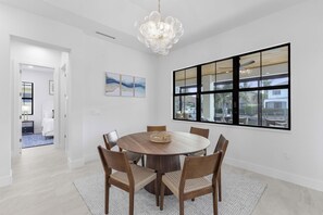 Un coin repas avec une table ronde en bois, six chaises et un lustre.