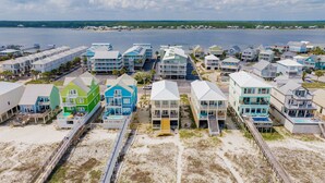 A coastal residential area with colorful houses, a beach, and a pier. - Luxury Gulf Front Retreat | Hot Tub | Elevator | Pet Friendly (Gulf Shores)