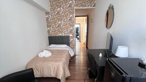 A hotel room with a bed, a desk, a chair, a TV, and a mirror. - HOTEL BRENTA  (Parma)