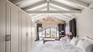 Un dormitorio con una cama grande, una pared de piedra y vistas por una ventana.